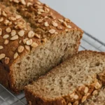 Delicious 4 ingredient banana bread with oats, freshly baked and sliced, revealing its moist texture with walnuts on top.