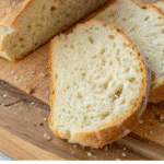 Delicious, freshly sliced Peasant-Style No-Knead Bread loaf on a wooden cutting board, showing its airy crumb.