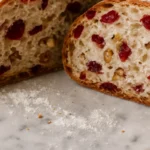 Whole cranberry nut bread loaf sliced open, revealing a fluffy interior with nuts and cranberries