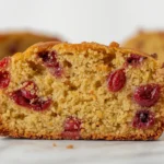 Close-up of a slice of moist lemon cranberry bread, showcasing the tender crumb and juicy cranberries.